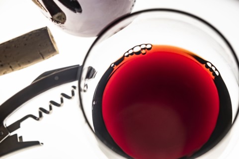 Glass of red wine with corkscrew and cork