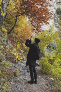 young woman photographing with smartphone in autumn forest