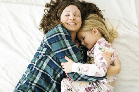 High angle view of mother and daughter in pajamas lying on bed