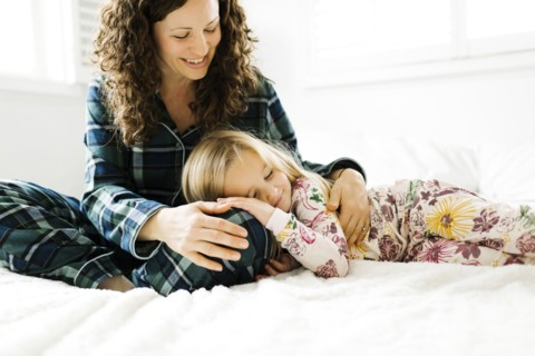 Mother and daughter hugging on bed