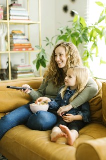 Mother and daughter with bowl of popcorn watching movie