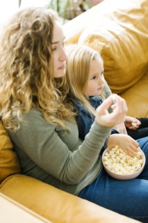 Mother and daughter with bowl of popcorn watching movie