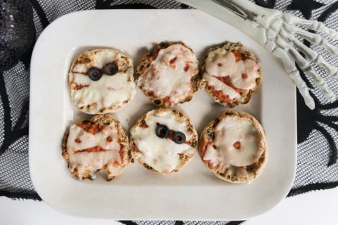 Plate of mini pizzas and hand of Halloween skeleton