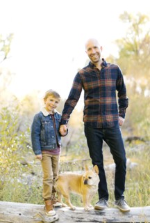 Father and son with pet French bulldog on fallen tree