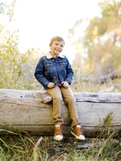 Smiling boy sitting on log