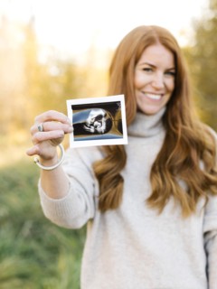 Smiling pregnant woman holding ultrasound photograph