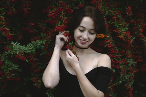 young woman standing by bush with red berries