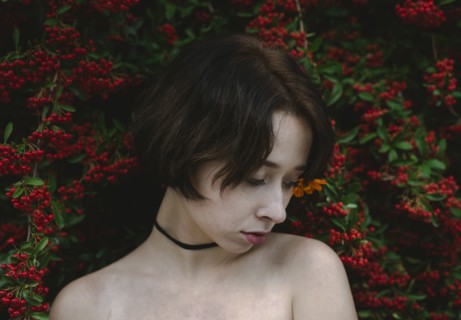 young woman standing by bush with red berries