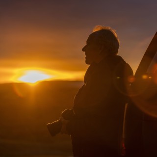 Senior man with camera at sunset