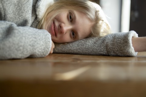 young woman in wool coat lying on cafe table