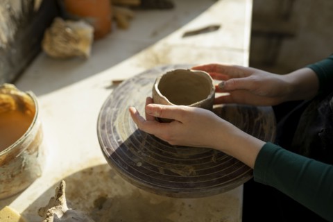 Hands of woman molding clay on potter's wheel