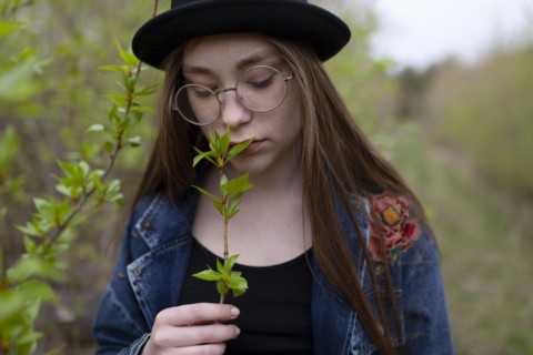 young woman smelling leaves on twig