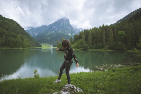 young woman balancing on rock by lake
