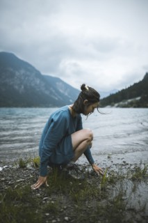 young woman crouching by lake