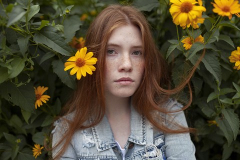 Teenage girl by bush with orange flowers