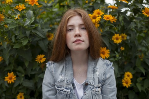 Teenage girl by bush with orange flowers