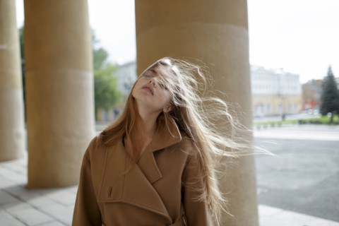 young woman with windblown hair by columns