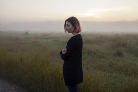 young woman in field at sunset