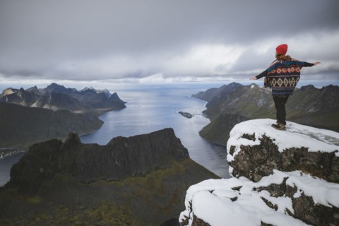 young woman in red hat and sweater on snowy mountain