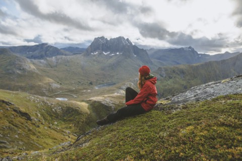 young woman in red jacket sitting on mountain