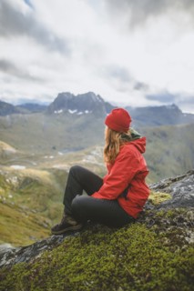young woman in red jacket sitting on mountain