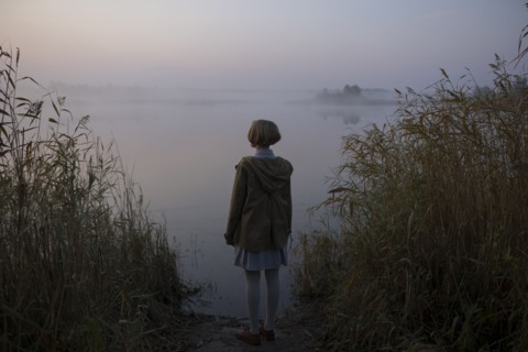 young woman by lake at sunset