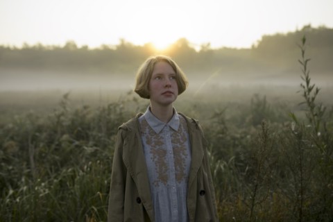 young woman in field at sunset