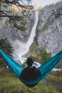 young man resting in hammock by waterfall