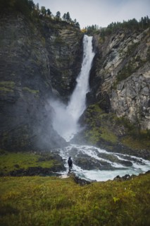 young man standing by waterfall