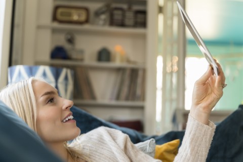 Woman using tablet while lying on sofa