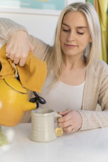 Woman making tea, pouring water from kettle