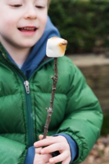 Boy watching roasted marshmallow on stick