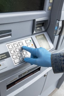 Close-up of gloved hand on keypad of ATM machine