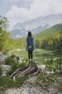 Germany, Bavaria, Eibsee, Young woman standing on stump by Frillensee lake in Bavarian Alps