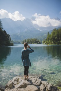 Germany, Bavaria, Eibsee, Young woman standing on rock at shore of Eibsee lake in Bavarian Alps