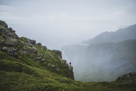 Norway, Lofoten Islands, Reine, Man looking at view from Reinebringen mountain during rain