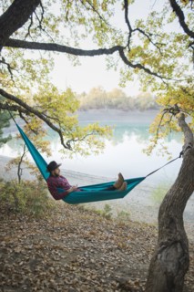 Italy, Man lying in hammock near lake