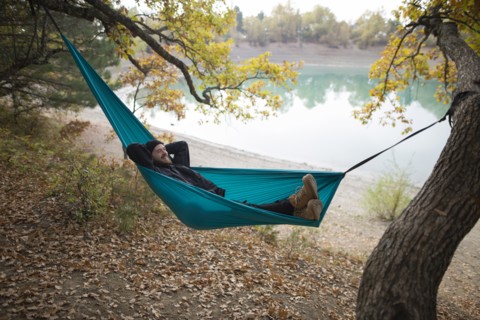 Italy, Smiling man lying in hammock near lake