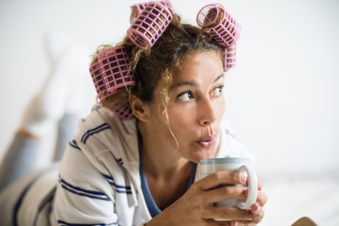Woman with hair curlers holding mug
