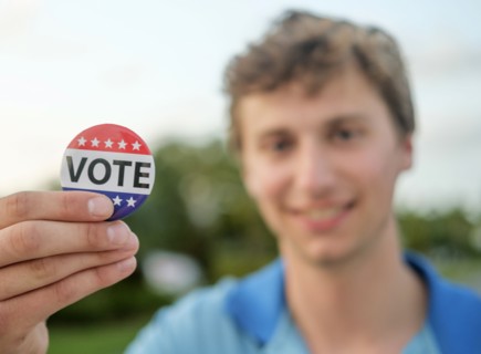 Smiling man holding vote button