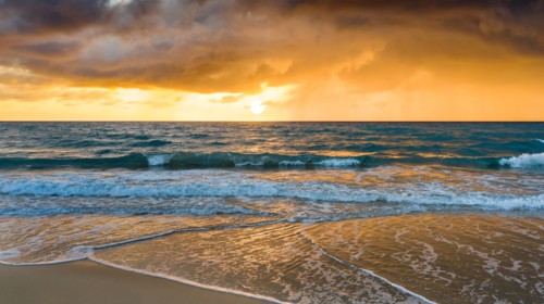 Beach under dramatic sky at sunset