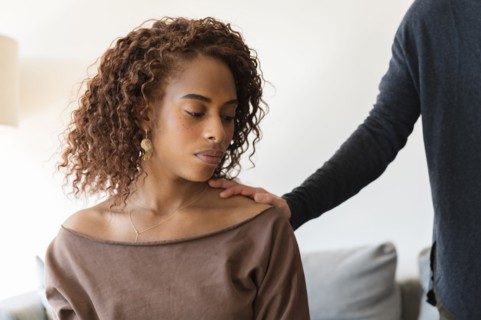 Person with their hand on sad woman's shoulder
