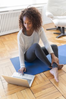 Woman using laptop on yoga mat