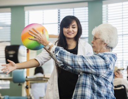 Senior woman holding ball at rehabilitation center