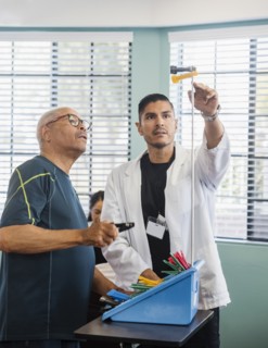 Doctor showing senior man pegs on pole at rehabilitation center