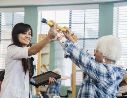 Smiling doctor helping senior woman hold pole