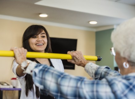 Smiling doctor helping senior woman hold pole