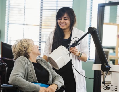Smiling doctor holding machine by senior woman