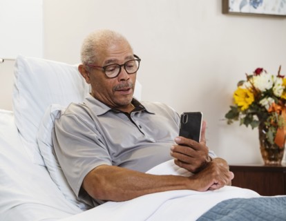 Senior man using smart phone in bed