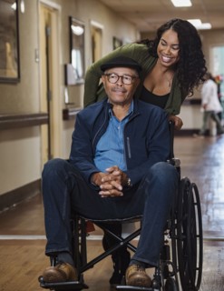 Smiling woman pushing senior man in wheelchair